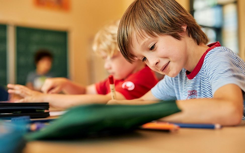 Deutschland: Ein Junge sitzt am Schreibtisch und schreibt in ein Heft