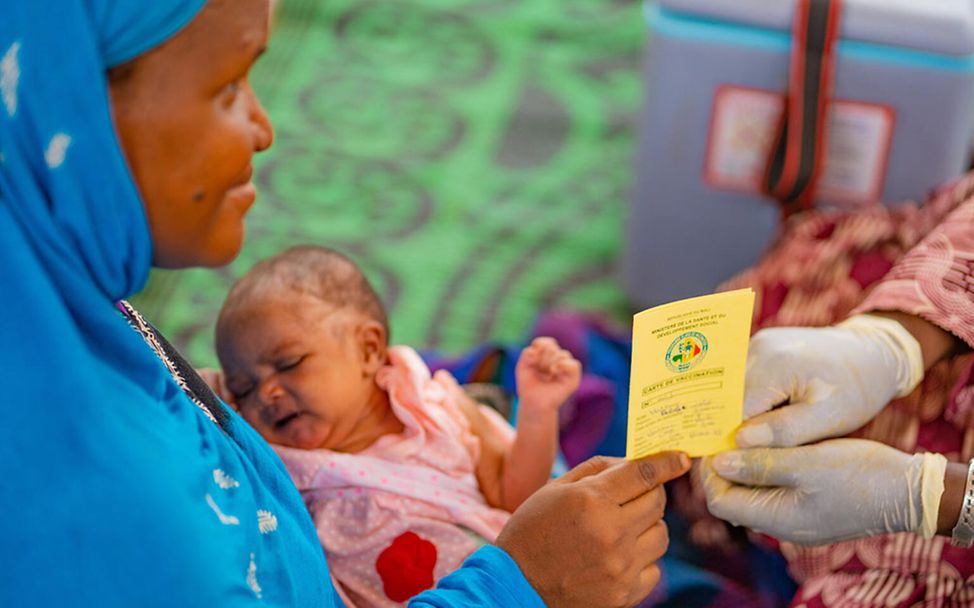 Malaria Impfung: Eine Mutter in Mali mit ihrem Baby auf dem Schoß bekommt ihren Impfausweis. 