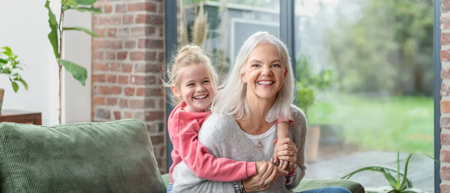 Eine Oma und ihre Enkelin sitzen gemeinsam auf dem Sofa