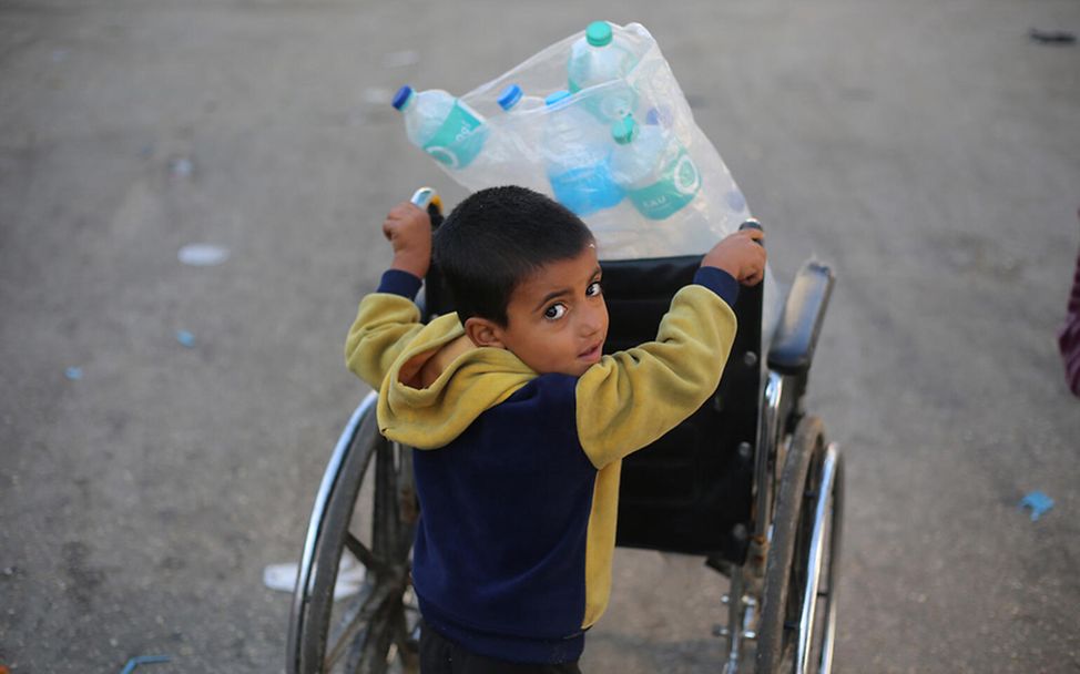 Gaza Kinder: Ein Junge transportiert leere Wasserflaschen, um sie mit Trinkwasser aufzufüllensser_UNI488857