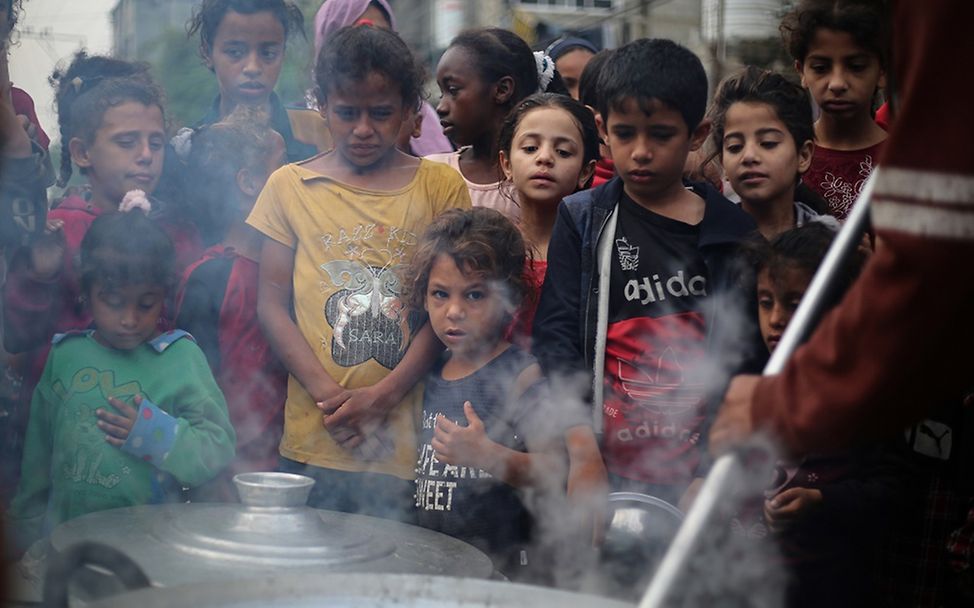 In den Straßen von Chan Yunis warten Kinder auf das Essen, das von einer Gemeinschaftsinitiative zubereitet wurde.