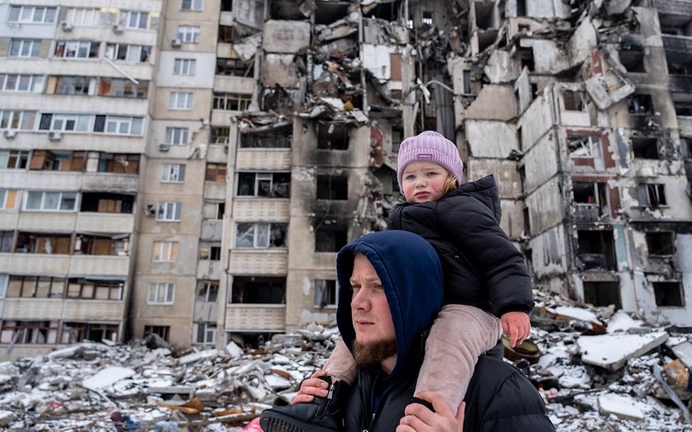 Ukraine: Ein Vater mit seiner Tochter vor einem zerstörten Haus