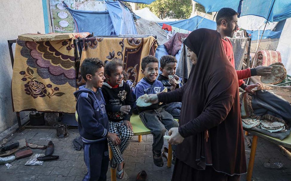 Kinder in Gaza Hunger: Eine Mutter gibt ihren Kindern etwas Fladenbrot