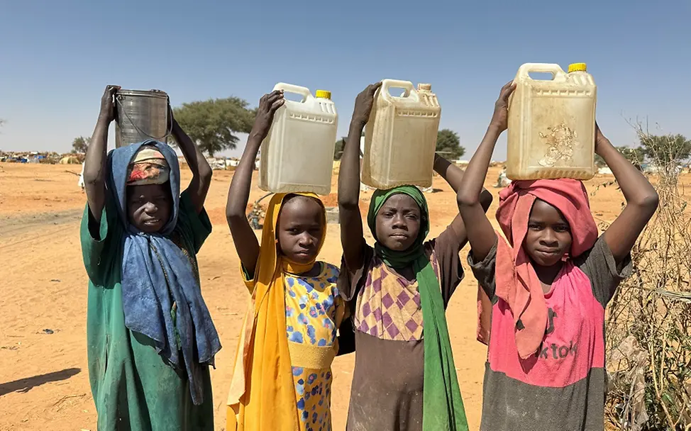 Sudan: So viele Kinder wie nie zuvor benötigen lebensrettende Hilfe | UNICEF/Le Du Eine Gruppe von Kindern in einem Flüchtlingscamp im Tschad trägt Wassereimer.