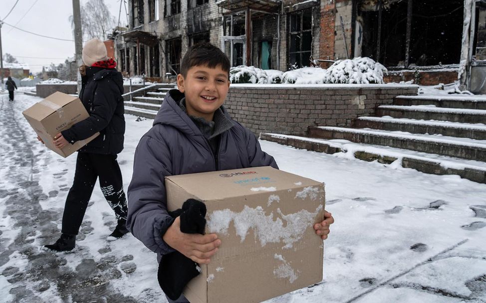 Kinder im Ukraine-Krieg: Ein Junge im Osten des Landes trägt einen UNICEF-Karton mit Hilfsgütern. 