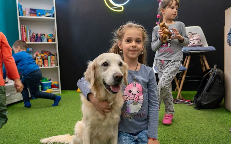 Kinder im Ukraine-Krieg: Ein Mädchen sitzt mit Therapiehund in einem UNICEF-Kinderzentrum. 