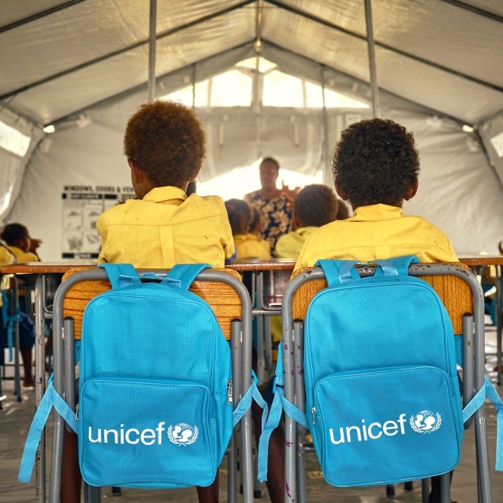 Schüler der Klasse 3 mit UNICEF-Rucksäcken in ihrem provisorischen Klassenzimmer im UNICEF-Zelt.