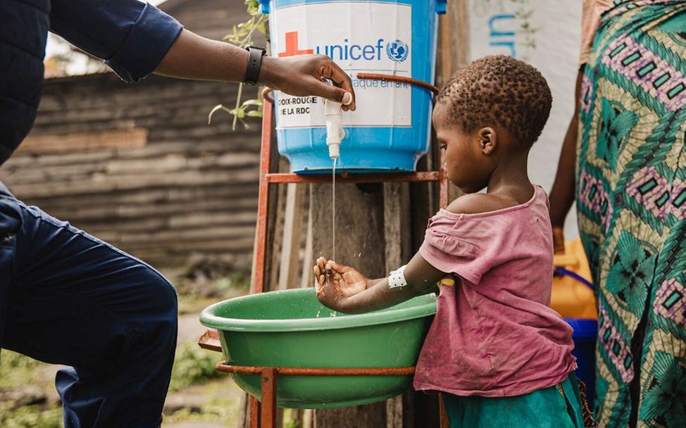 Hygieniker desinfiziert Mädchenhände im Afya Sake CTC, Nord-Kivu, DR Kongo.