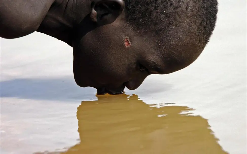 Junge trinkt aus dem Fluss am Rande des Dorfes. © UNICEF/Cranston Junge trinkt aus dem Fluss am Rande des Dorfes. © UNICEF/Cranston