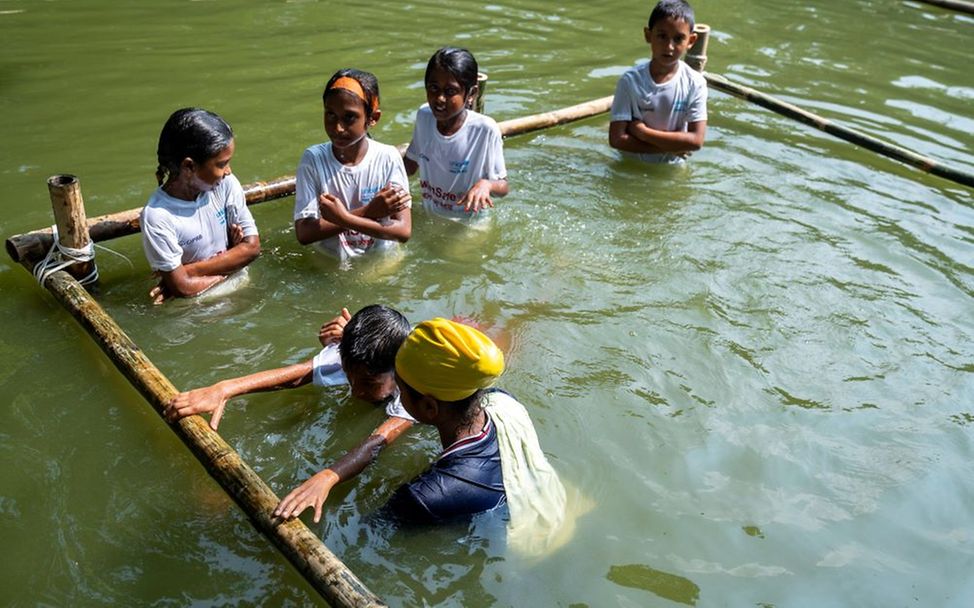 In einem geschützten Bereich zeigt Mim den Kindern erste Schwimmübungen.