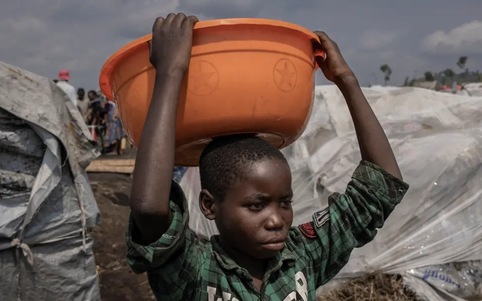 Merci Shivima, 12, trägt eine Schüssel mit Wasser im Flüchtlingslager Bulengo in der DR Kongo | © UNICEF/UN0791491/Ndebo Weltflüchtlingstag: Merci Shivima, 12, trägt eine Schüssel mit Wasser im Flüchtlingslager Bulengo in der DR Kongo (Februar 2023)
