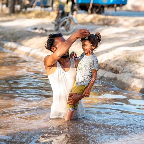 Hitze Kinder: Vater kühlt Tochter mit Wasser während Hitze in Pakistan.