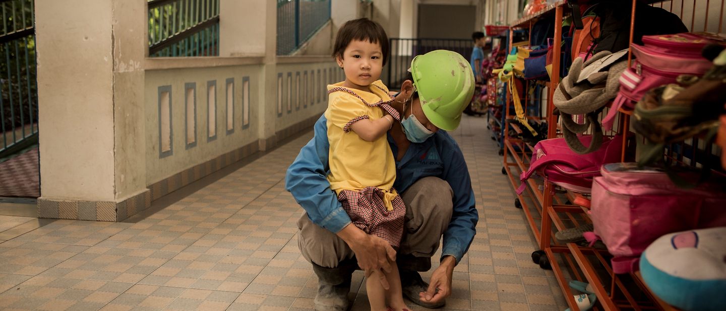 Herr Nguyen Van Hung zieht seiner Tochter Nguyen Thi Tien Schuhe an.