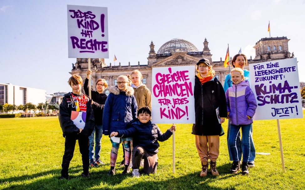 Kinderrechte leben: Kinder stehen mit Demo-Plakaten vor dem Reichstag.