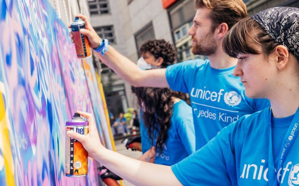 Kinderrechte leben: Ehrenamtliche sprühen ein Graffiti.