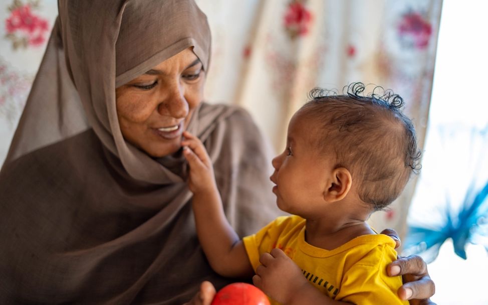 Sabna Mohamed spielt mit ihrer 9 Monate alten Tochter in ihrem Haus im Dorf Wager in der Region North Delta, Sudan.