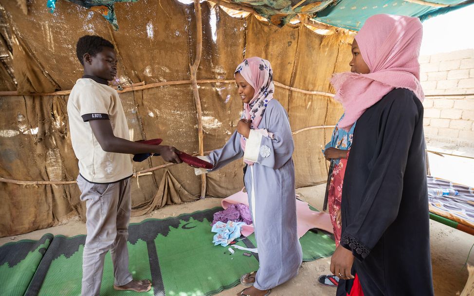 Sudan: Samer verschenkt Binden an Mädchen, die er selbst genäht hat.