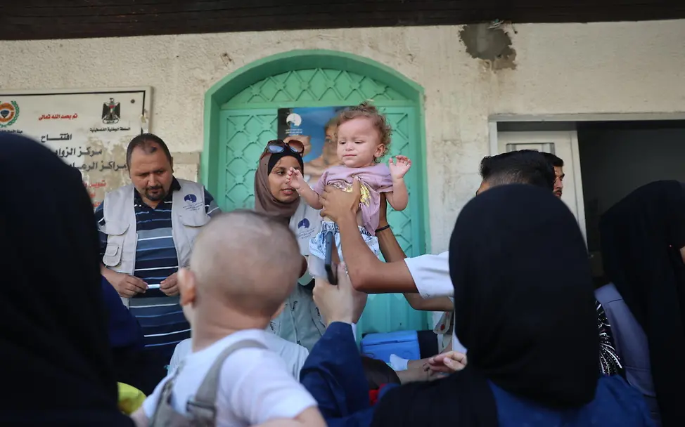 Impfkampagne gegen Polio in Gaza | © UNICEF/UNI636610/El Baba Ein Kleinkind wird von einem Gesundheitshelfer hochgehoben