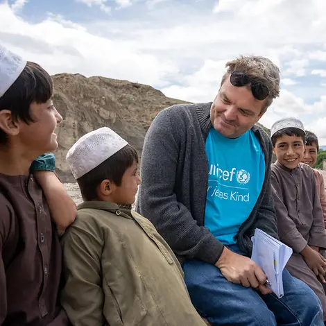 Daniel Timme in Afghanistan Daniel Timme sitzt mit mehreren Kindern im Gespräch auf einer Mauer