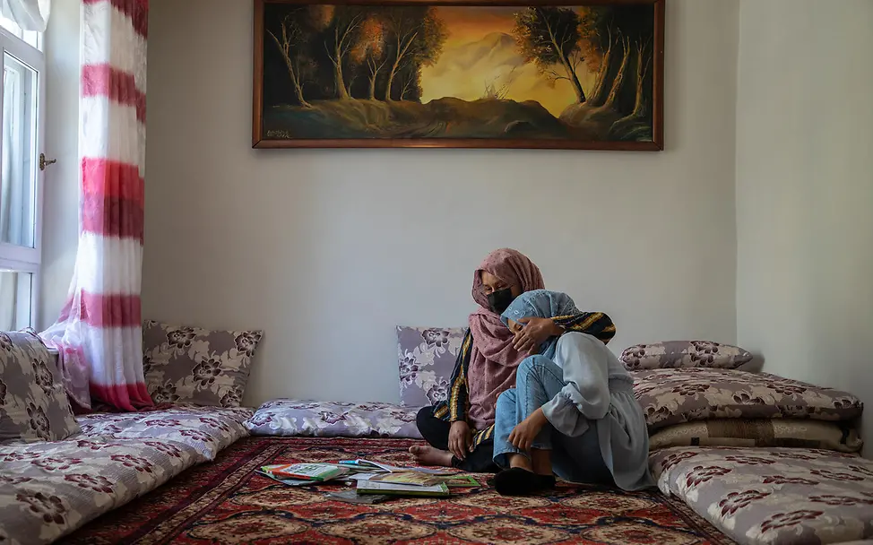 Mutter und Tochter in Afghanistan | © UNICEF/UNI590567/Meerzad Eine Mutter umarmt auf dem Boden sitzend ihre weinende Tochter