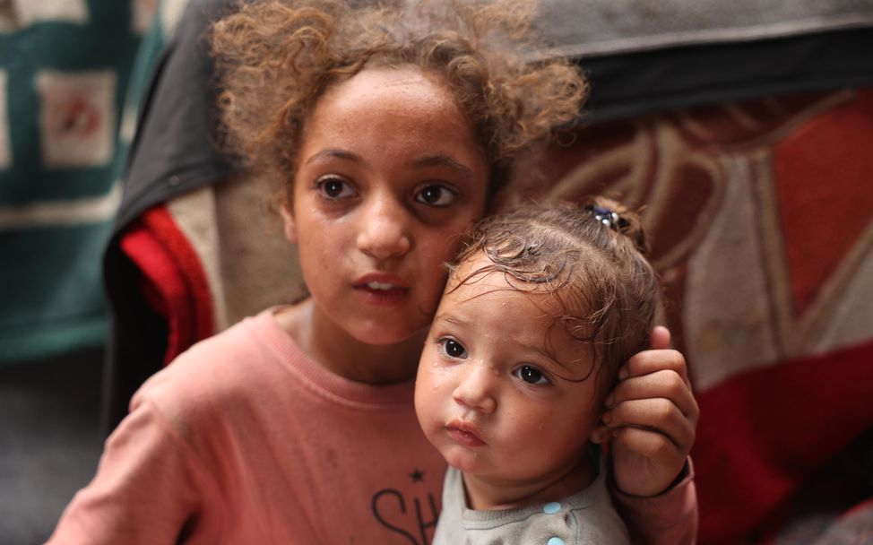 Rama, 11 Jahre alt, mit ihrer einjährigen Schwester Malak in ihrem Zelt in Deir al-Balah, Gazastreifen.