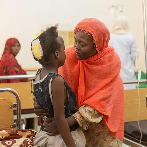 Der Krieg im Sudan bedroht Kinder | © UNICEF/UNI631172/Elfatih Mutter umarmt ihre verletze Tochter in einem Krankenhaus