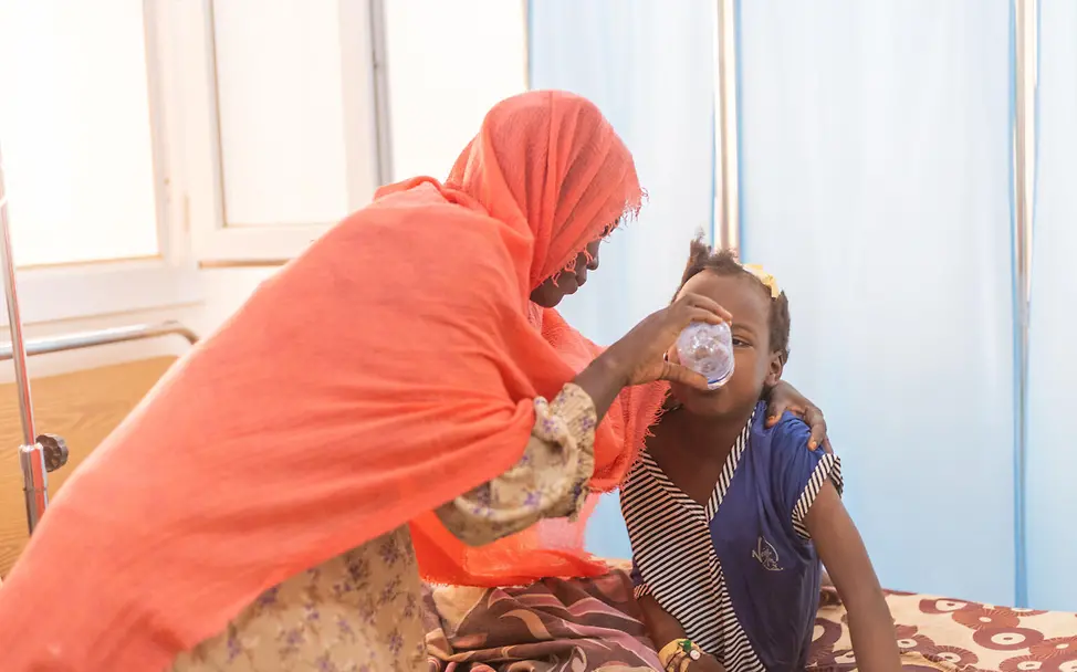 Krieg im Sudan bedroht Kinder | © UNICEF/UNI631173/Elfatih Eine Mutter gibt ihrer 8-jährigen Tochter etwas zu trinken