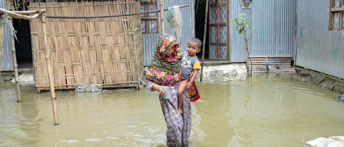 Eine Mutter und ihr Kind waten durch die Fluten in Kurigram Bangaldesch (2024)