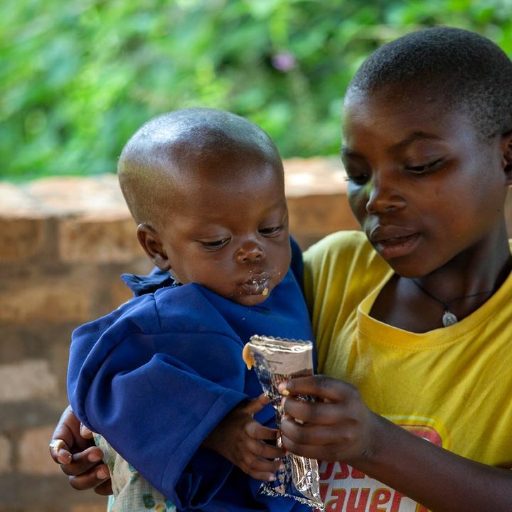 Burundi Mangelernährung: Ein Mädchen füttert seinen kleinen mangelernährten Bruder mit Erdnusspaste