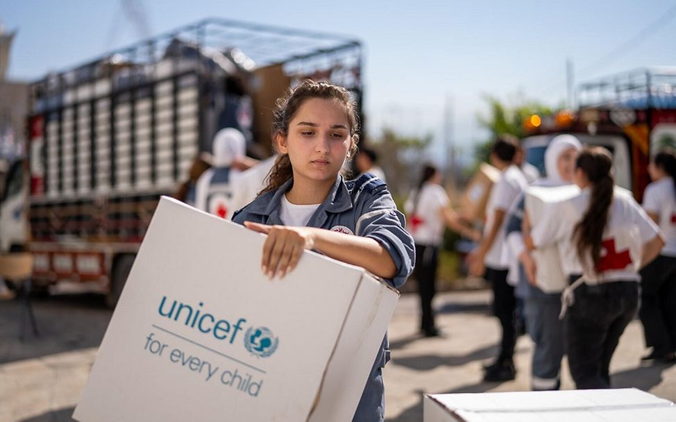 Libanon Kinder: Eine Helferin vom libanesischen Roten Kreuz trägt eine Box mit UNICEF-Hilfsgütern