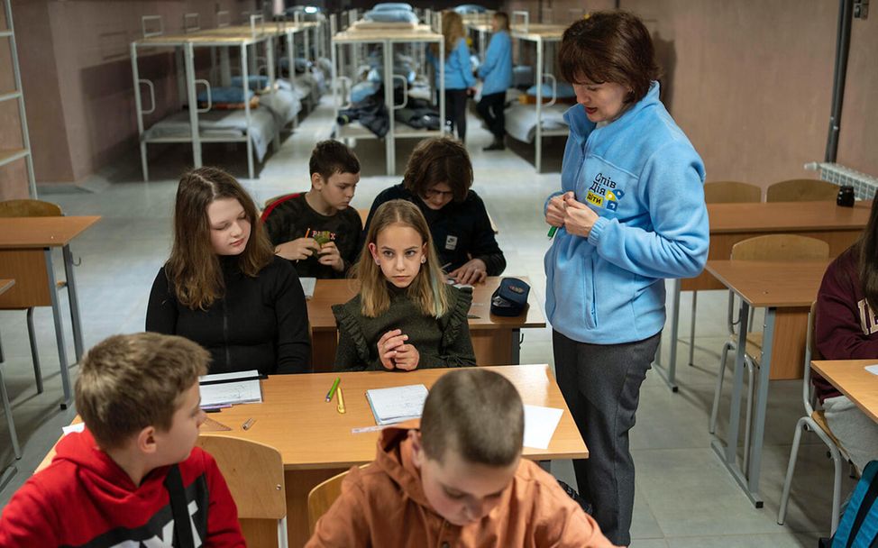 Kinder im Krieg: Eine Lehrerin unterrichtet Mädchen und Jungen in einem Luftschutzbunker