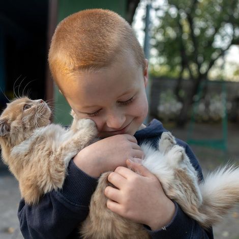 Ukraine Winter Hilfe: Ein Junge in der Region Charkiw kuschelt mit seiner Katze