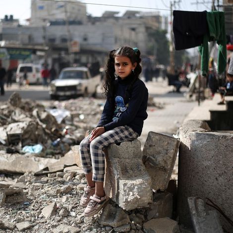 Ein kleines Mädchen sitzt auf Trümmern eines Hauses in Gaza