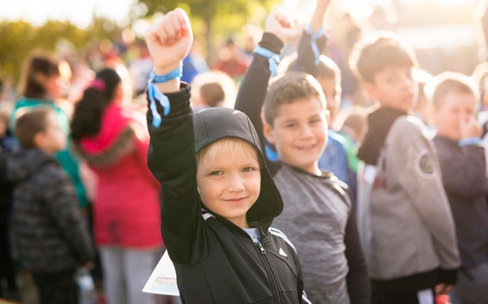 Kinderrechteschulen: Ein Junge streckt seine Faust in die Höhe beim Schülerlauf der Schule am Mohnweg.