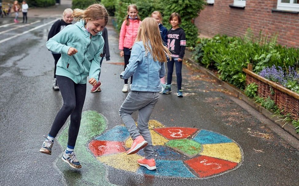 Kinderrechteschulen: Schüler*innen spielen auf dem Schulhof ein Hüpfspiel