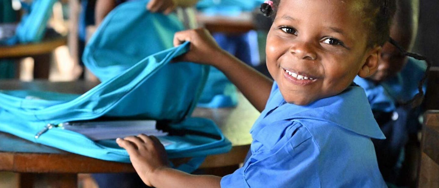 Spenden Bildung: Eine Grundschülerin in Kamerun bekommt einen neuen Schulrucksack mit Schulmaterial 