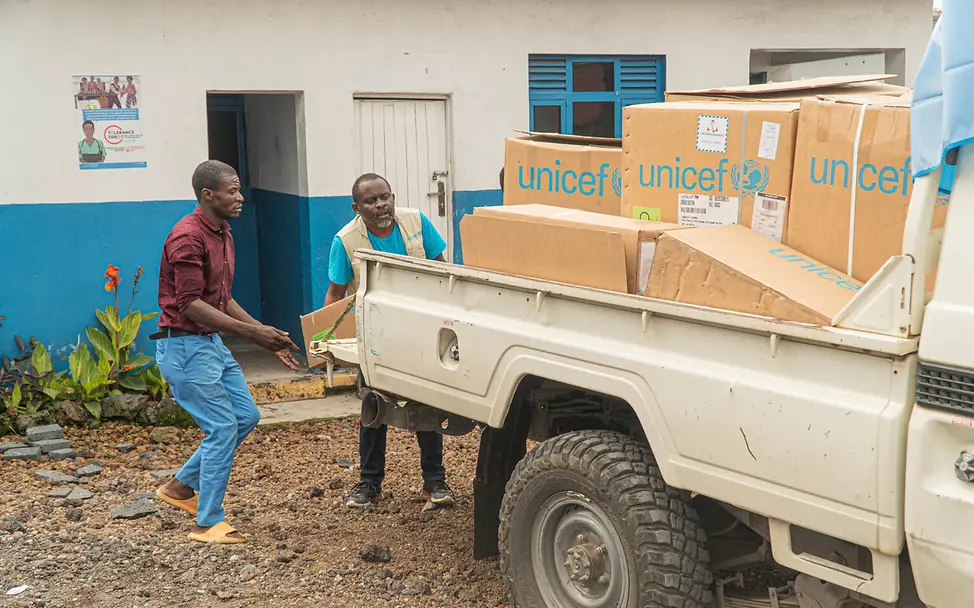 UNICEF Hilfsgüter werden organisiert | © UNICEF/UNI729043/Ushindi Zwei Männer räumen UNICEF HIlfsgüter auf einen Wagen