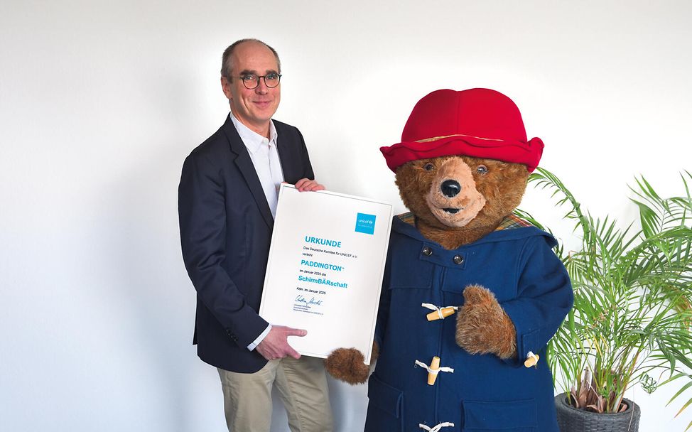 Christian Schneider, Geschäftsführer UNICEF Deutschland, gemeinsam mit dem frischgebackenen SchirmBÄRen Paddington™ 