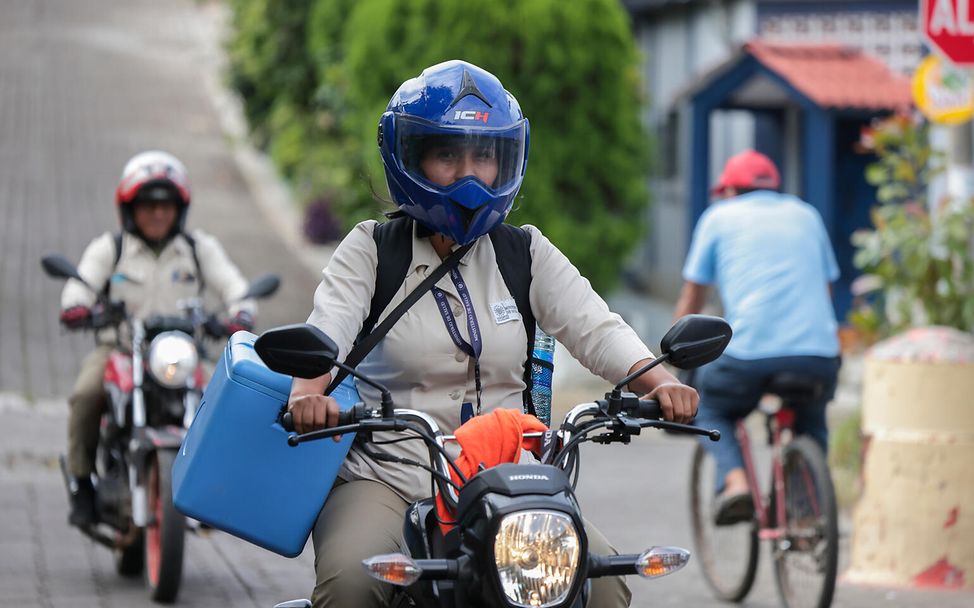 El Salvador: Glenda fährt mit ihrer Kühlbox voller Impfungen Motorad.