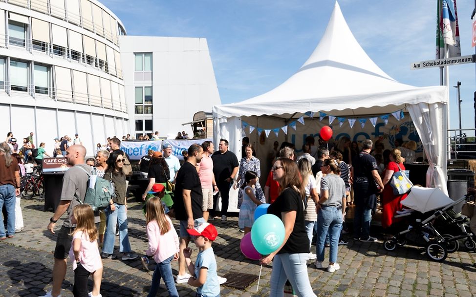 Kinder und Erwachsene stehen vor einem Zelt von UNICEF auf dem Festival. 