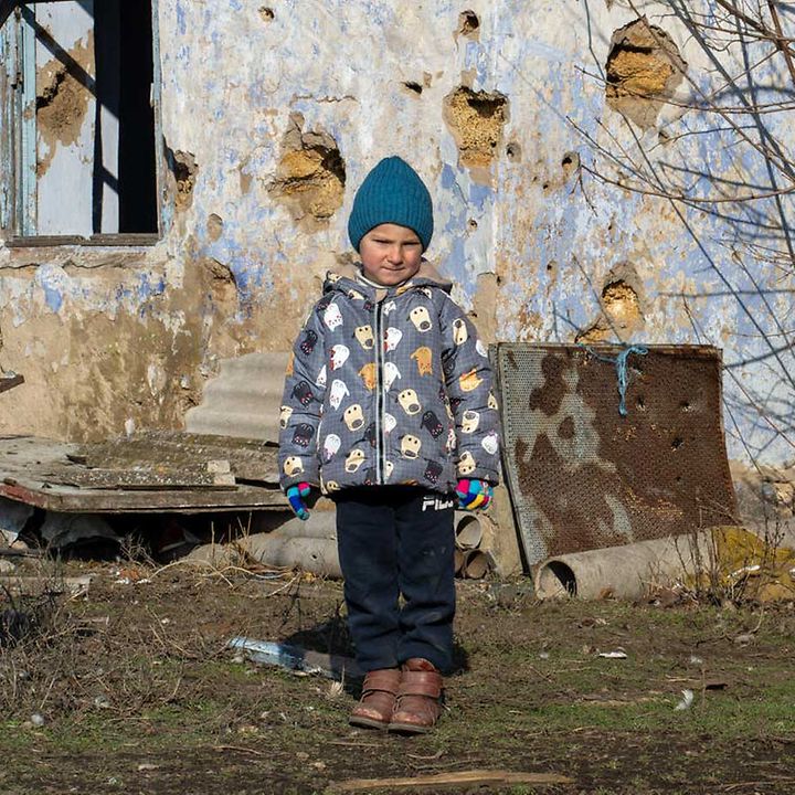 Kinder im Ukraine-Krieg: Ein Junge im Osten der Ukraine steht vor seinem bei Angriffen stark beschädigten Zuhause