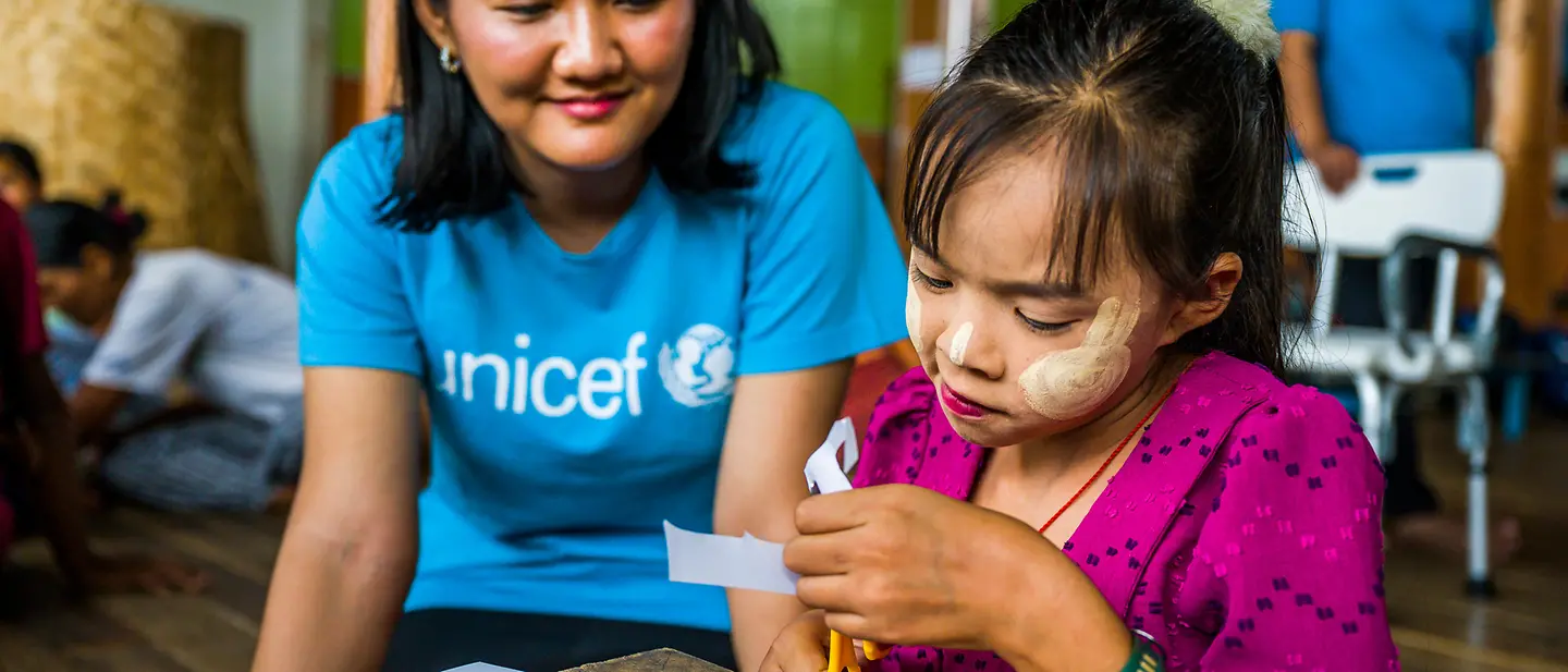 Myanmar spenden: Eine UNICEF-Helferin beobachtet ein Mädchen in einem Lernzentrum beim Basteln