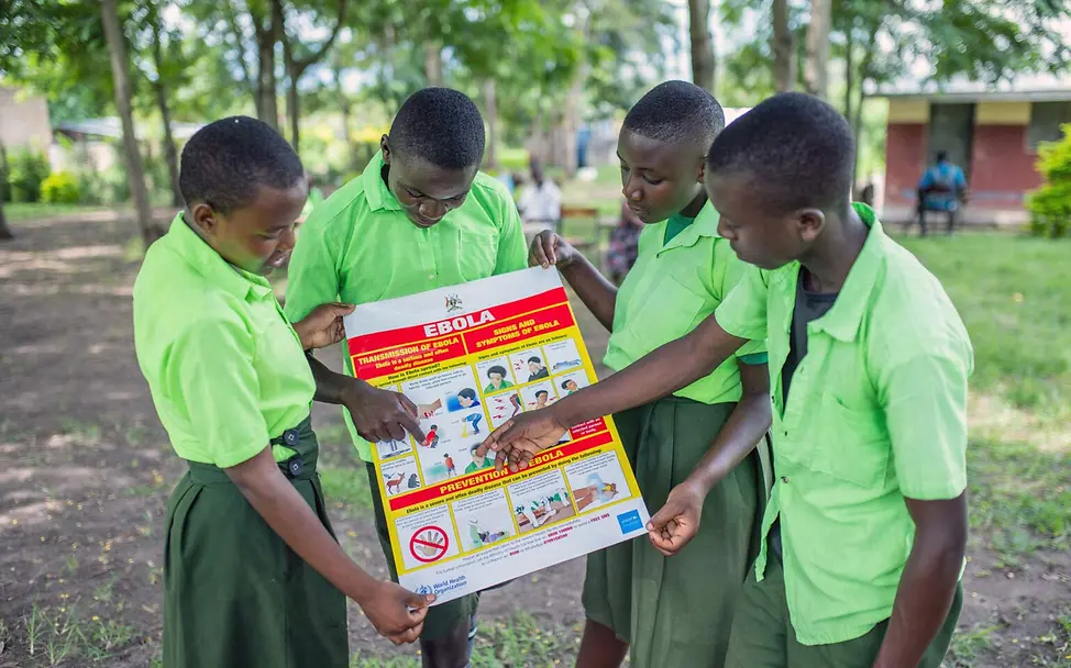 Ebolaaufklärung: Schülerinnen und Schüler in Uganda sehen sich gemeinsam ein Infoplakat zu Ebola an. 