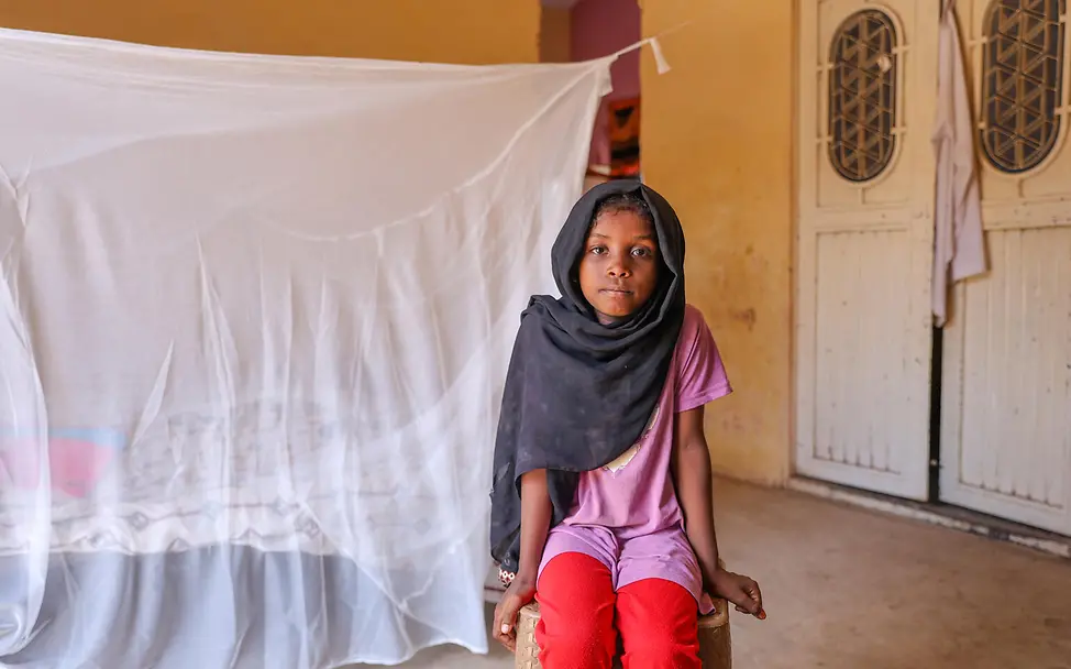 Sudan Krieg: Ein Mädchen sitzt vor einem mit einem Moskitonetz geschützten Bett. 