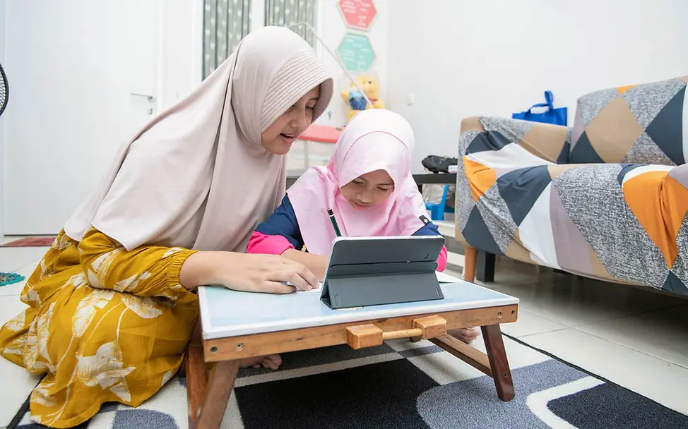 Digitale Gewohnheiten: Eine Mutter in Indonesien zeigt ihrer Tochter zuhause etwas am Tablet. 