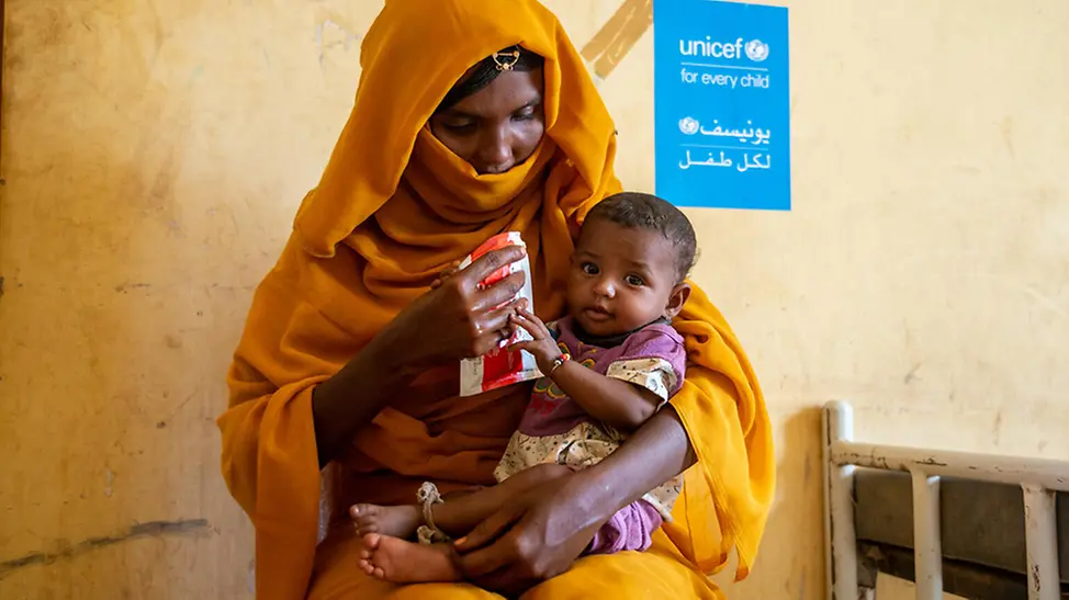 Sudan: Mutter gibt Kind Erdnusspaste.