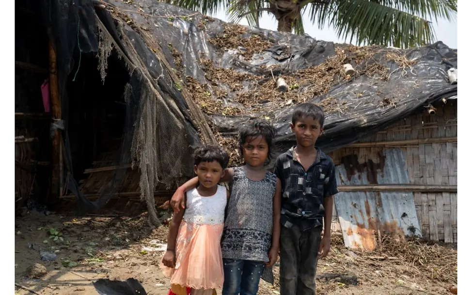 © UNICEF/Himu Kinder stehen vor einem durch Zyklon zerstörtem Haus.