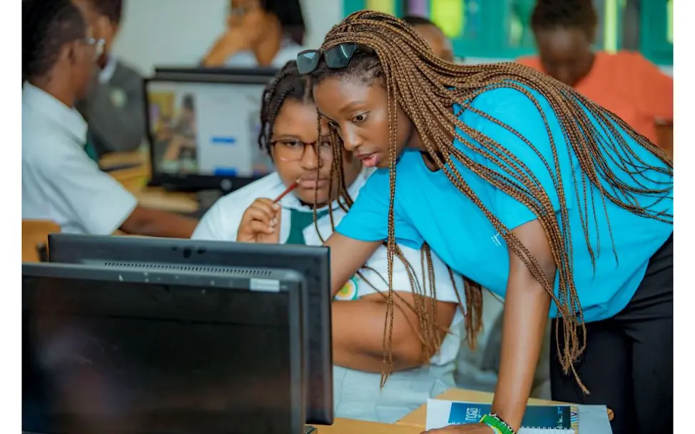 © UNICEF/Iyakaremye Ruanda: Zwei junge Frauen in einem Klassenzimmer schauen auf einen Bildschirm.