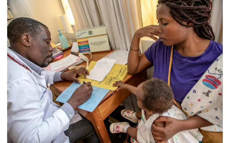 © UNICEF/Schermbrucker  Mutter sitzt mit ihrem Kind beim Arzt.
