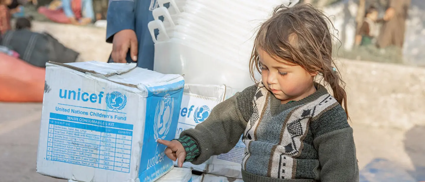 Afghanistan: Mädchen zeigt auf Hilfsgüter von UNICEF.